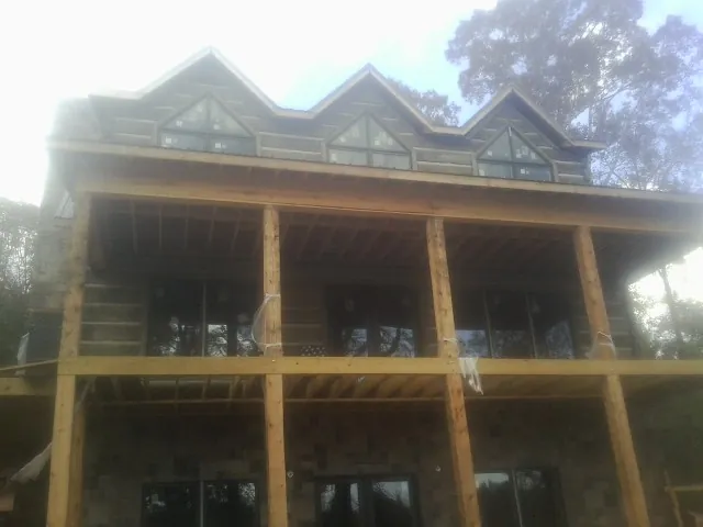 Dormers and porch framing on a large log home under construction — Roof Coating work by our crew in Mc Coy