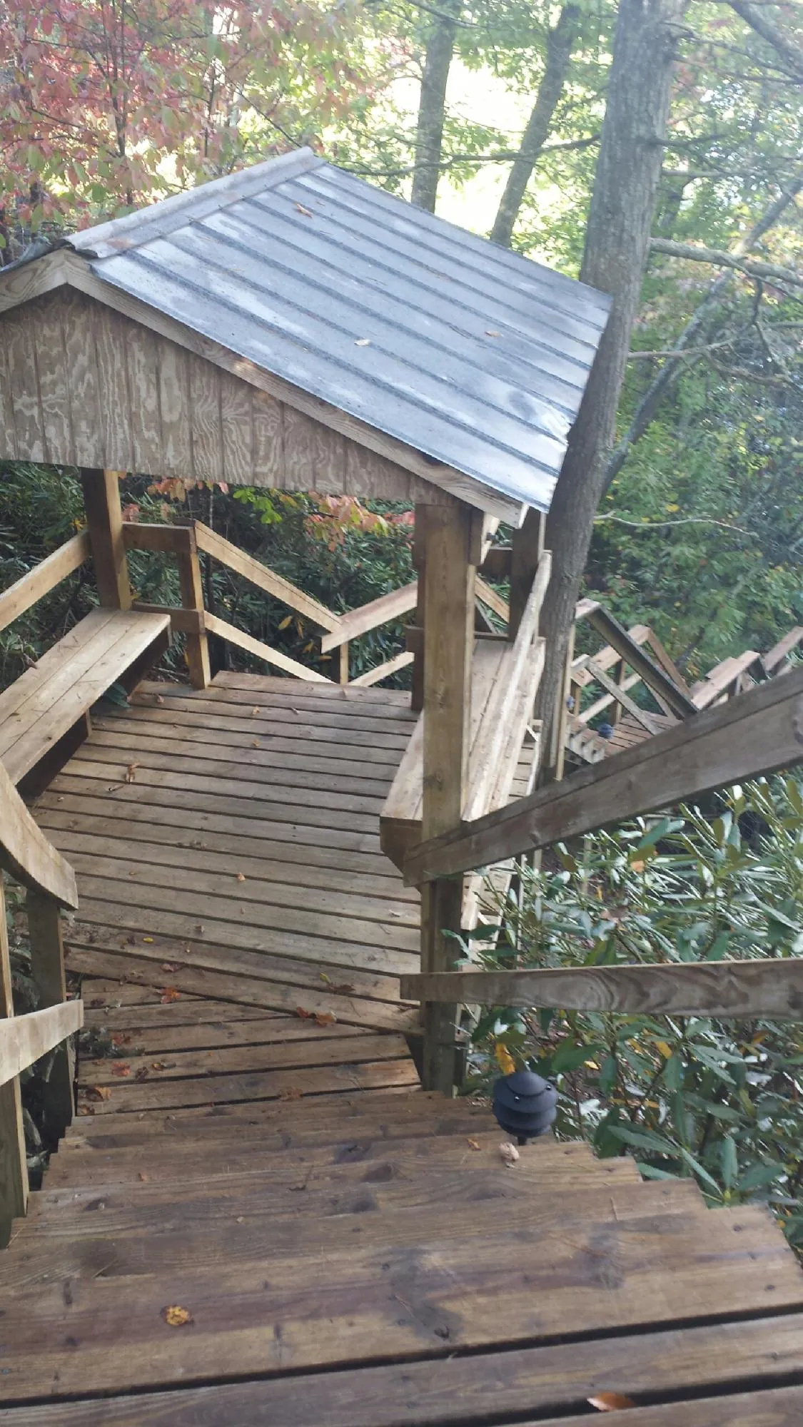 Metal roofed shelter over wooden steps on a wooded walkway — Skylight Repair & Installation work by our crew in Mc Coy