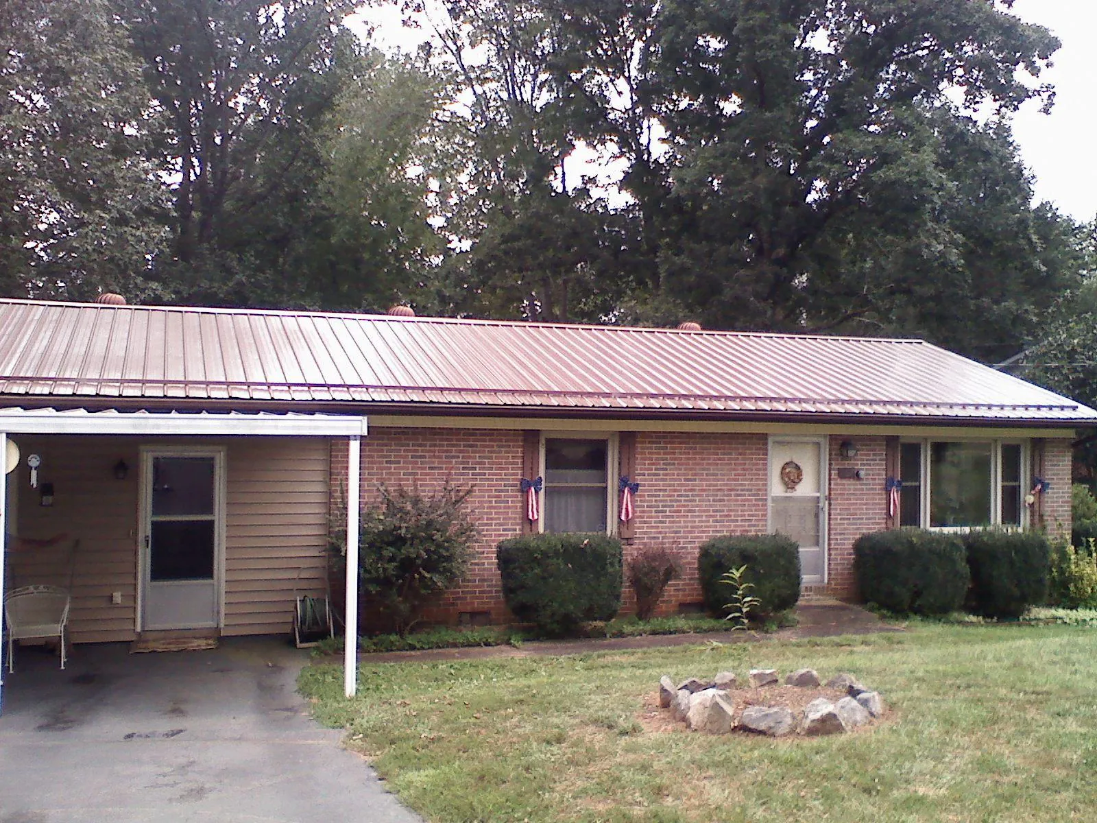 Bronze metal roof and carport on a brick ranch home — Roof Repair work by our crew in Mc Coy