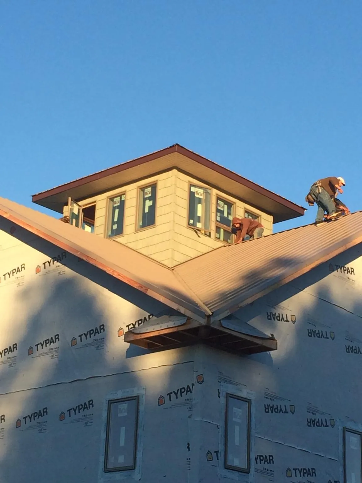Roofers working around a rooftop cupola on a new metal roof at sunset — Roof Waterproofing in Mc Coy by Roofing Brothers
